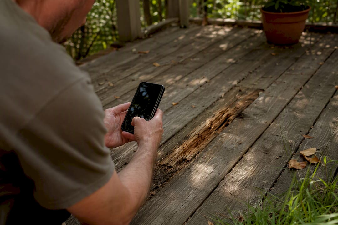 Homeowner photographing damaged deck boards